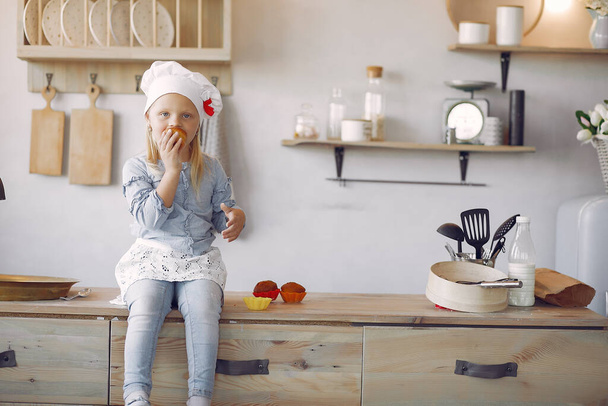 Cute little girl in a kitchen with cupcake - Фото, зображення