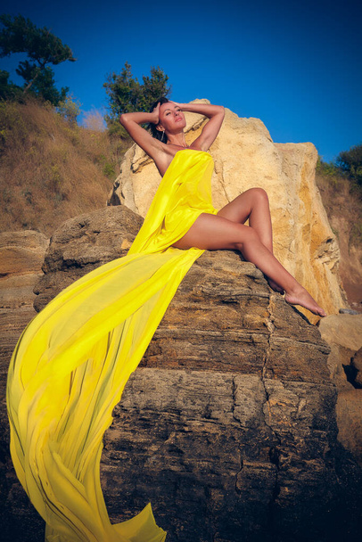 beautiful woman in yellow cloth on the rock - Foto, Imagem