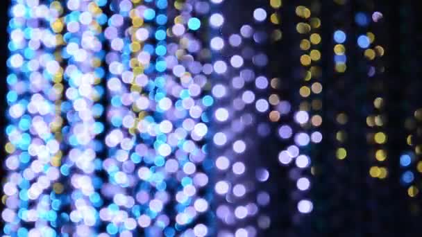 Iluminación de luz de una guirnalda de luces intermitentes en forma de bokeh de blanco, azul, púrpura y oro. El concepto de unas vacaciones, Navidad, iluminación, fiesta
. - Metraje, vídeo