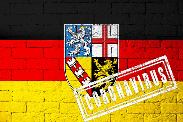 Σημαία των περιφερειών της Γερμανίας Saarland με αρχικές αναλογίες. σφραγίδα του Coronavirus. υφή τούβλου τοίχου. Ιός Κορόνα. Στα πρόθυρα πανδημίας COVID-19 ή 2019-nCoV. - Φωτογραφία, εικόνα