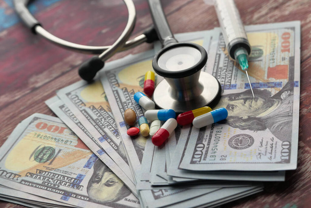 Close up of cash, pills and stethoscope on table  - Фото, зображення
