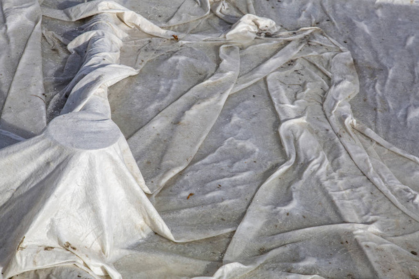 Текстурированная поверхность плотной защитной ткани зимой покрывает дренажную систему городского фонтана
 - Фото, изображение