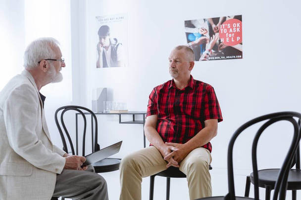 Older man talking with psychologist in the office - Fotó, kép