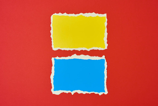 Two ripped paper torn edge sheets on red background. Template with piece of color paper - 写真・画像