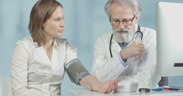 Arzt in seiner Praxis misst Blutdruck seiner Patientin - Filmmaterial, Video
