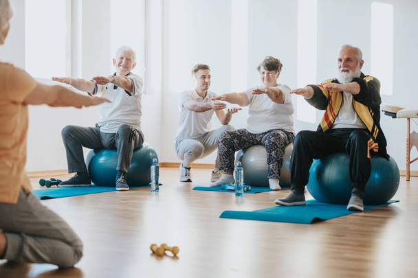 Grupo de personas mayores haciendo ejercicio sobre bolas juntas en un gimnasio
 - Foto, Imagen