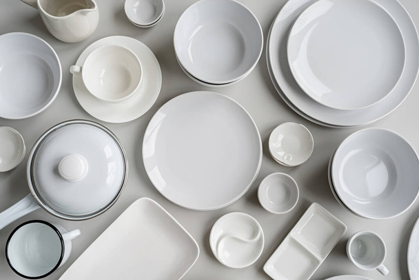 piles of white ceramic dishes and tableware top view on gray background - Foto, imagen