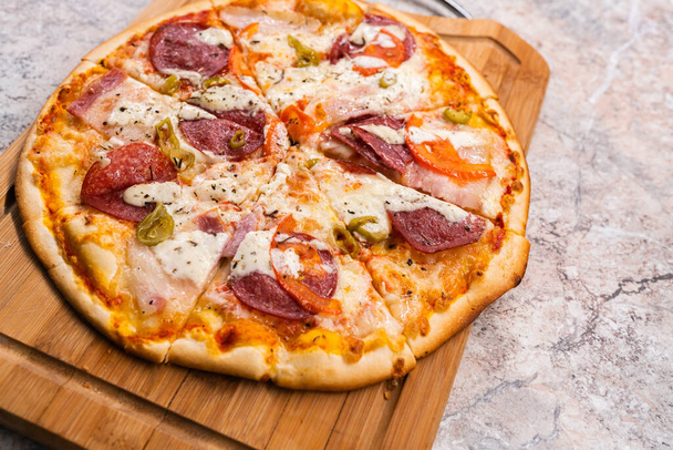 Homemade pizza on a wooden cutting Board on the table closeup - 写真・画像