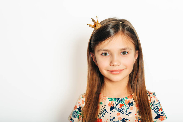 Студийный портрет красивой маленькой девочки в крохотной короне принцессы, позирующей на белом фоне
 - Фото, изображение