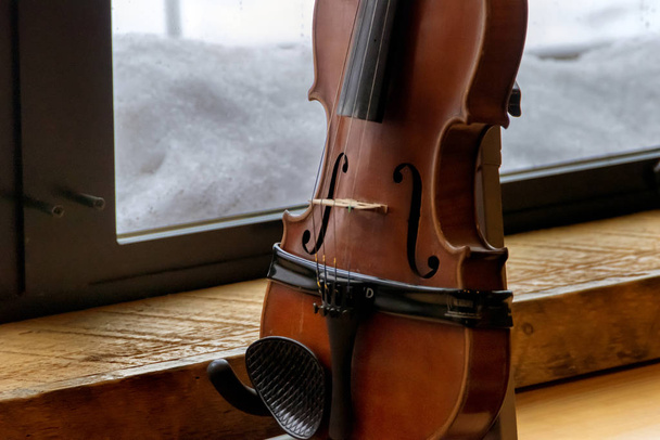 雪の窓の前でユニークなバイオリンのクローズアップ - 写真・画像