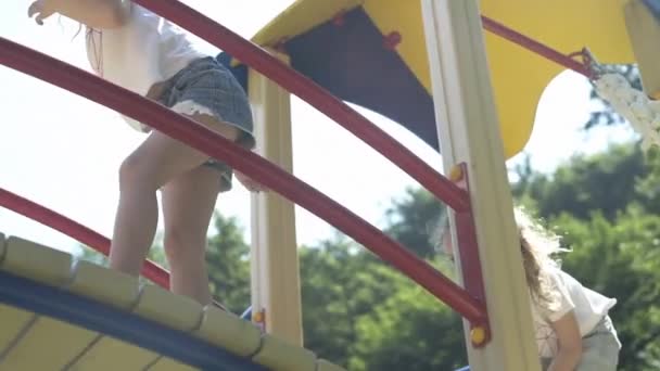 Girls ride on swings, children's slides, carousels, on the playground - Materiał filmowy, wideo