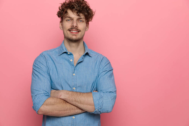 happy young guy smiling and crossing arms, standing on pink background - Φωτογραφία, εικόνα