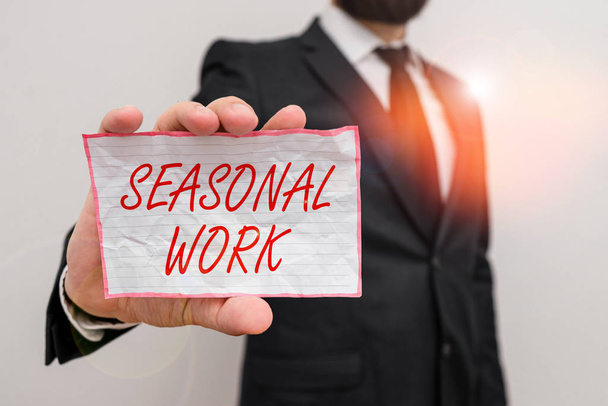 Writing note showing Seasonal Work. Business photo showcasing Temporary employment which the workload occurs certain season Male human wear formal work suit with office look hold book. - Foto, Bild