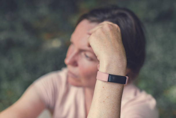 Female hiker with smart fitness tracker bracelet while resting in nature, selective focus - Фото, изображение