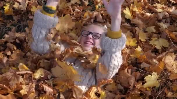 glimlachend tiener meisje liggend op gevallen herfst bladeren - Video