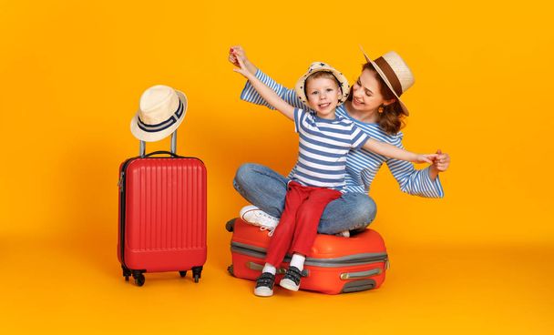 Καλό ταξίδι! οικογένεια των ταξιδιωτών μητέρα και παιδί με βαλίτσες εισιτήρια και διαβατήρια σε χρωματιστό κίτρινο backgroun - Φωτογραφία, εικόνα