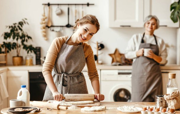 onnellinen perhe isoäiti vanha äiti anoppi ja miniä tytär kokki keittiössä, vaivaa taikina ja leipoa eväste
 - Valokuva, kuva