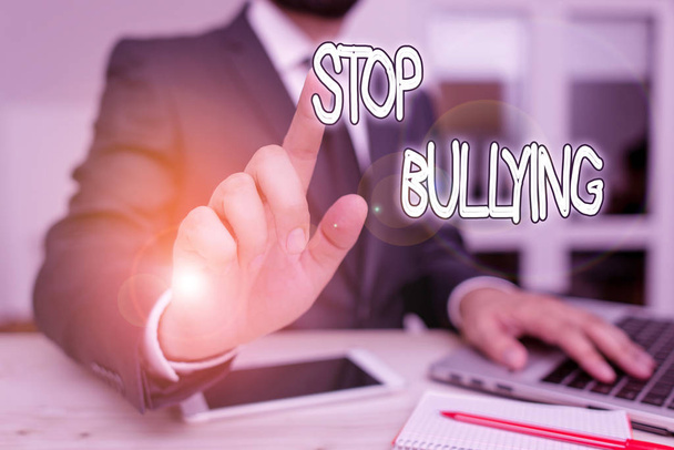 Handwriting text Stop Bullying. Concept meaning stop the aggressive behaviour among school aged children Male human wear formal clothes present presentation use hi tech smartphone. - Foto, afbeelding