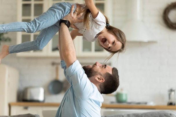 Przeszczęśliwy ojciec bawiący się z małą córeczką w domu - Zdjęcie, obraz