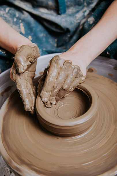 Women working on the potter's wheel. Hands sculpts a cup from clay pot. Workshop on modeling on the potter's wheel. - Photo, Image
