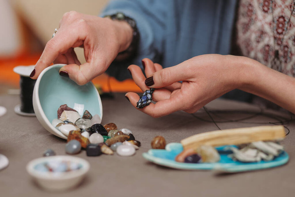 Vrouw die handgemaakte edelstenen juwelen maakt, thuiswerkplaats. Artisan vrouw maakt sieraden. Kunst, hobby, handwerk concept - Foto, afbeelding