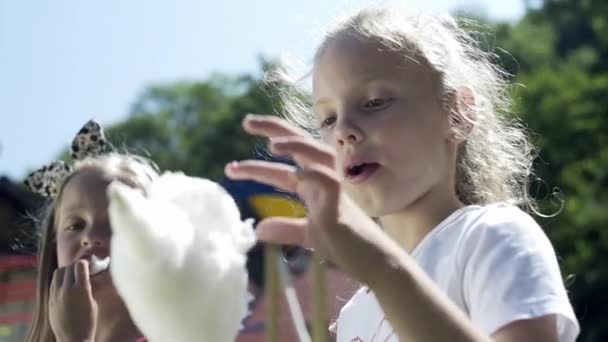 Dívky jedí cukrovou vatu na hřišti - Záběry, video