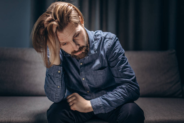 Mature man sitting on couch and feeling depressed - Fotoğraf, Görsel