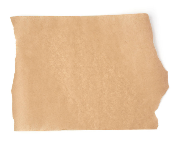 stuk bruin perkament papier met gescheurde randen geïsoleerd op een witte achtergrond, plaats voor een inscriptie, element voor een ontwerper - Foto, afbeelding