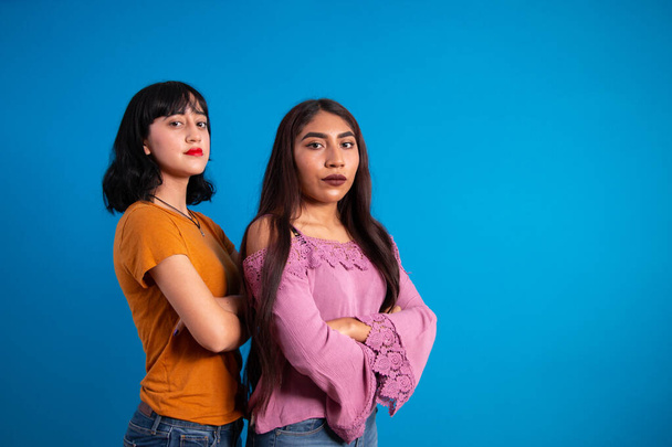 Kaksi nuorta ja vahvaa latinonaista naista poseeraamassa ristissä
 - Valokuva, kuva
