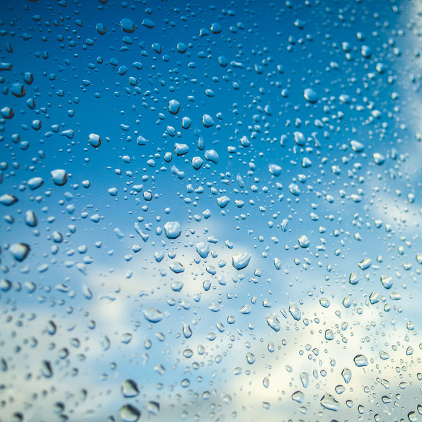 Капли воды на оконном стекле с голубым небом
 - Фото, изображение