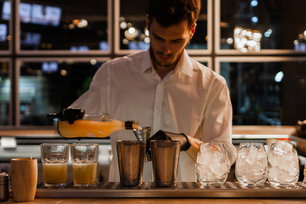 Profesjonalny młody barman pracujący w nocnym klubie. Koncepcja koktajlu - Zdjęcie, obraz
