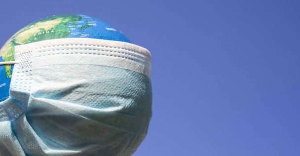 coronavirus wereldalarm - chirurgisch masker op wereldbol - Foto, afbeelding