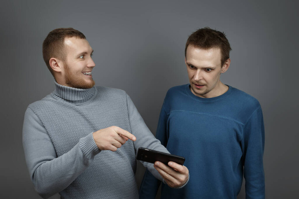 Two men with excitedly looking at the smartphone - Фото, изображение