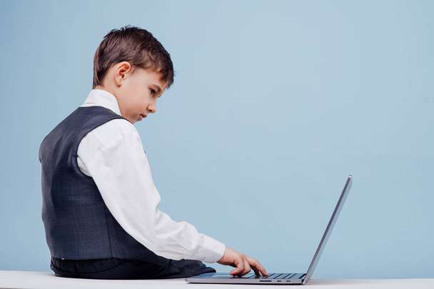 Back view of seriously little boy typing on laptop - Zdjęcie, obraz