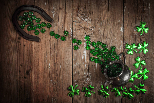 St. Patricks Day composition. Shamrocks, rusty horseshoe and silver pot on vintage style wood background. St.Patrick's day holiday symbol. Top view, copy space. - Photo, Image
