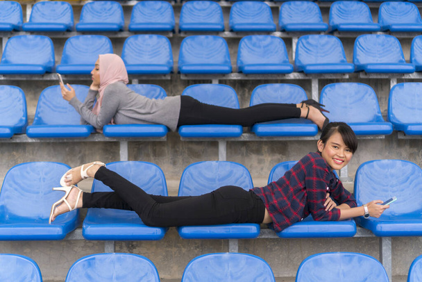 Studentisches Lifestyle-Konzept, süßes asiatisches Mädchen mit Smartphone auf der Bank - Foto, Bild