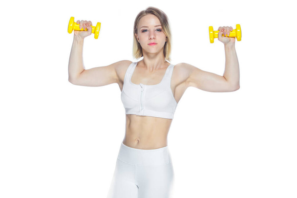 Fitness woman working out with yellow dumbbells showing her muscles on white background - Zdjęcie, obraz