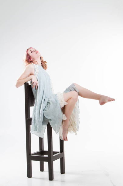 Die junge Blondine sitzt auf einem Barhocker. Studioporträt - Foto, Bild