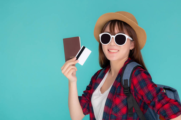 Piękna młoda azjatycka kobieta nosić kapelusz i okulary przeciwsłoneczne z pokazem karty kredytowej i paszportu do podróży letniej podróży odizolowany na niebieskim tle, podróż dziewczyna na wakacjach z finansowania płatności na karcie. - Zdjęcie, obraz
