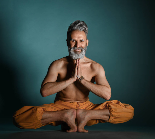 Old man with grey beard doing yoga, pilates, fitness training, stretching exercise, asana or balance workout on floor - Φωτογραφία, εικόνα
