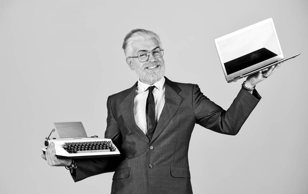 Образовательный сайт. компьютер или печатную машинку. новые и старые технологии. современный цифровой бизнес. Винтажная пишущая машинка. Счастливый бизнесмен использует ретро-пишущую машинку и современный ноутбук. зрелый мужчина с окрашенной бородой
 - Фото, изображение