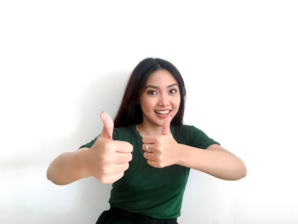 Sorrindo menina asiática em greent t-shirt mostrando polegares para cima
 - Foto, Imagem