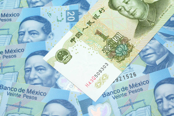 Nahaufnahme einer grünen, chinesischen Yuan-Banknote, Nahaufnahme auf einem Hintergrund blauer mexikanischer Zwanzig-Peso-Scheine. Schuss im Makro - Foto, Bild