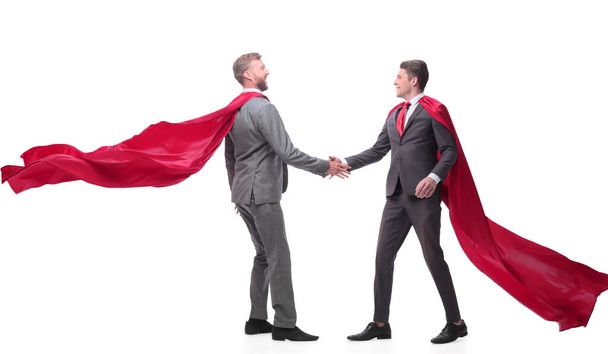 business partners in superhero cloaks shaking hands. - Foto, Bild