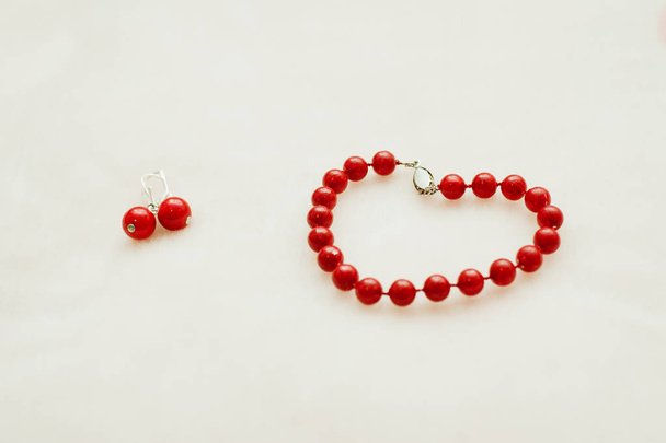 Red jewelry: bracelet and earrings with beads on a white background. - Fotoğraf, Görsel