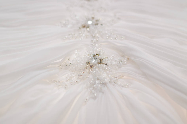 Stoffhintergrund. Perlen auf einem weißen Hochzeitskleid. - Foto, Bild
