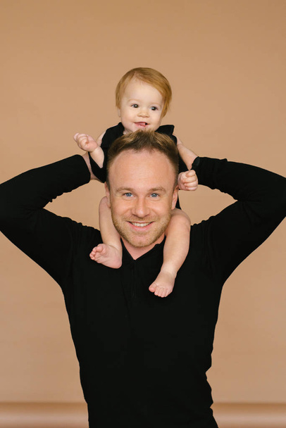 Dad holds a one-year-old daughter on a beige background. Fatherly love. Father's day. - Fotografie, Obrázek