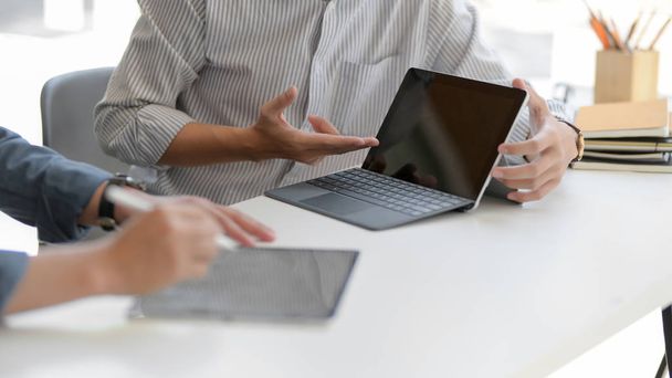 Cam duvardaki ofis odasındaki beyaz masada dijital tabletlerle çalışmalarına danışmanlık yapan iki işadamının görüntüsü. - Fotoğraf, Görsel