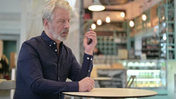 Angry Old Man Talking on Smartphone in Cafe - Felvétel, videó