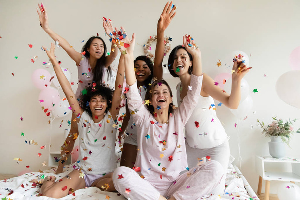 Aufgeregte Mädchen werfen Konfetti und feiern auf Party - Foto, Bild
